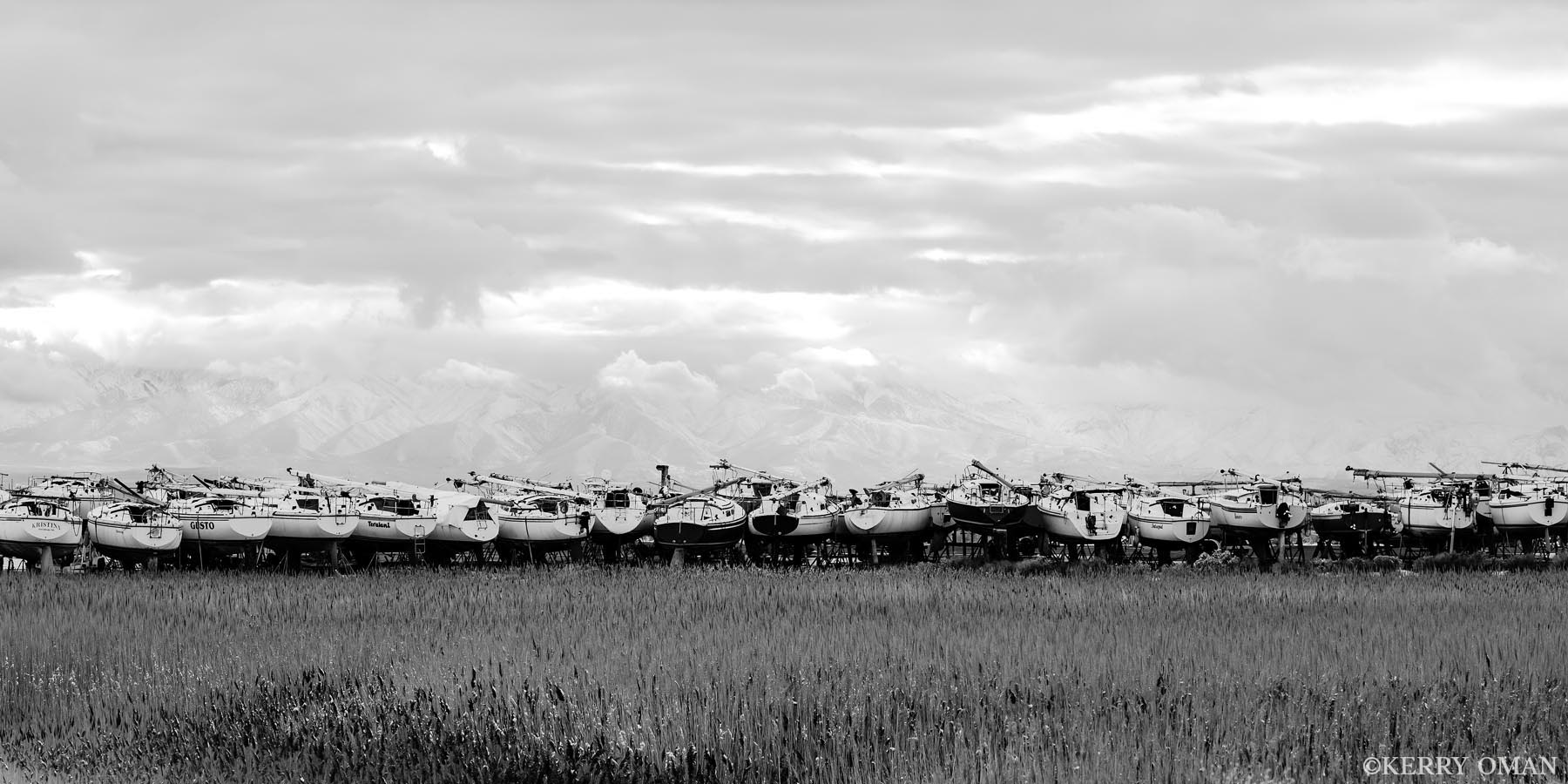 The Waiting Season A long row of sailboats rests in dry dock at the edge of the Great Salt Lake, waiting out the still season beneath a snow-veiled...