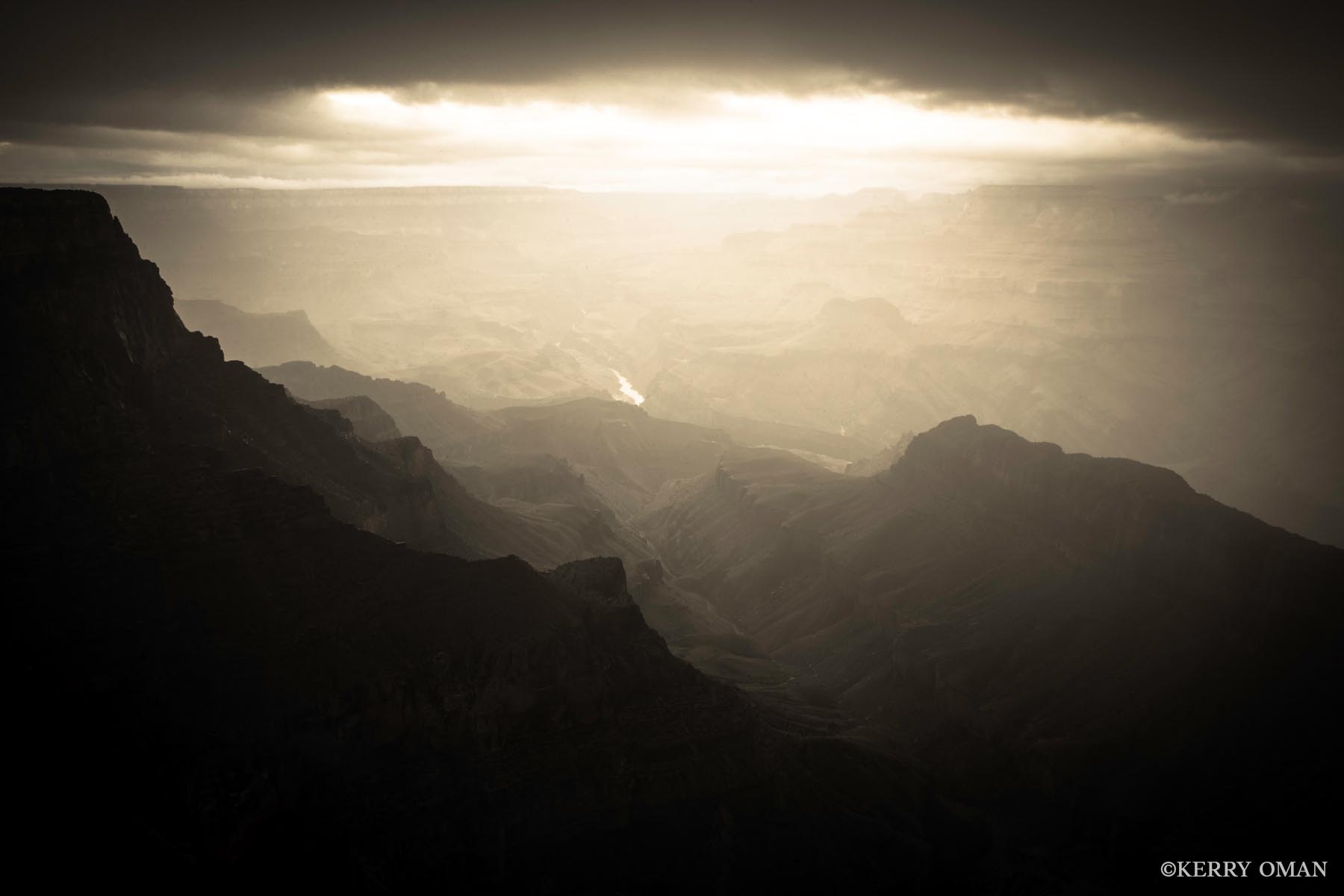 River of Light As evening settles over the Grand Canyon, a break in the clouds allows a narrow shaft of light to illuminate the path of the...