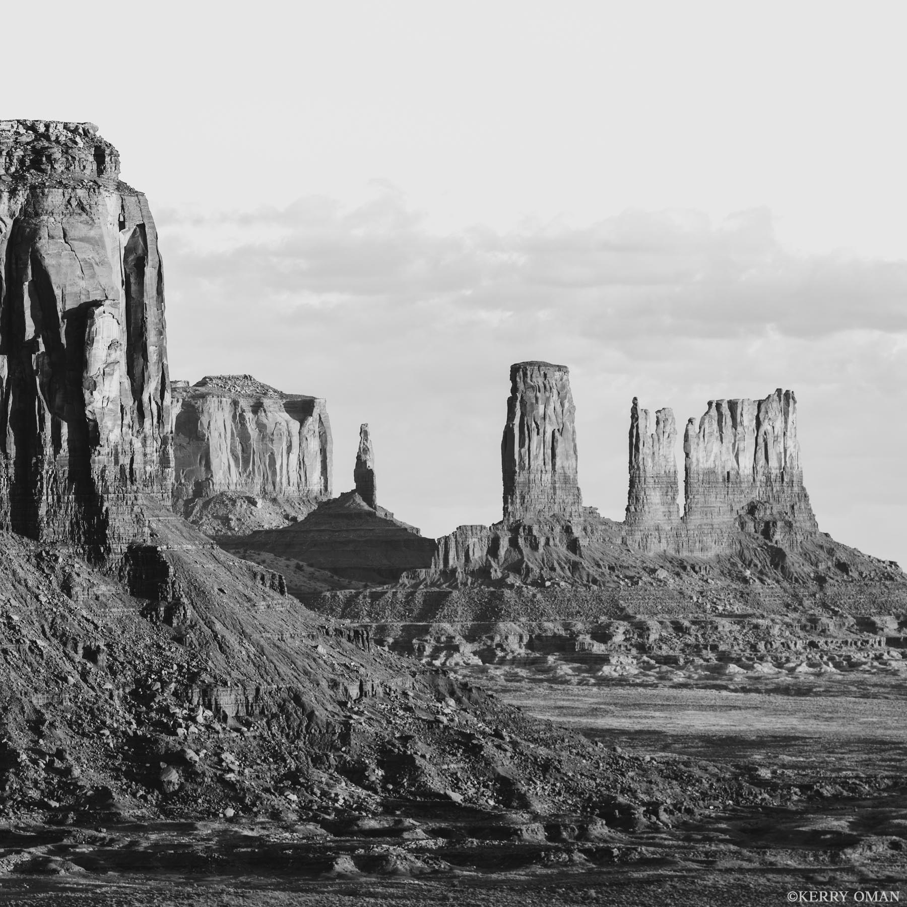 Echoes in Stone and Shadow In this black-and-white landscape of Monument Valley, towering sandstone buttes rise like ancient monuments carved by wind, time...