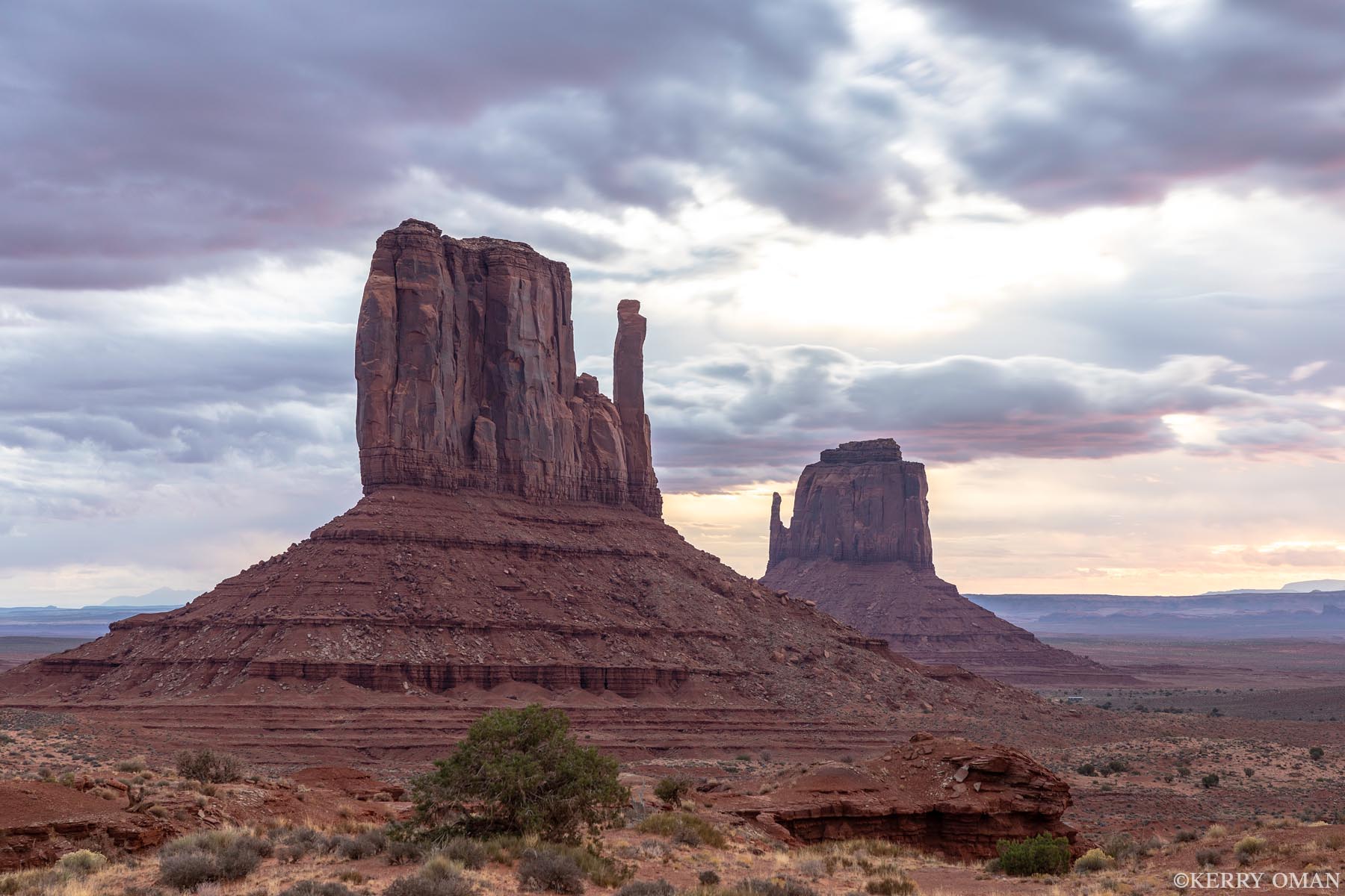 Under a Quiet Sky Clouds drift over Monument Valley as the iconic West and East Mitten Buttes rise from the desert floor. The soft, diffused light...
