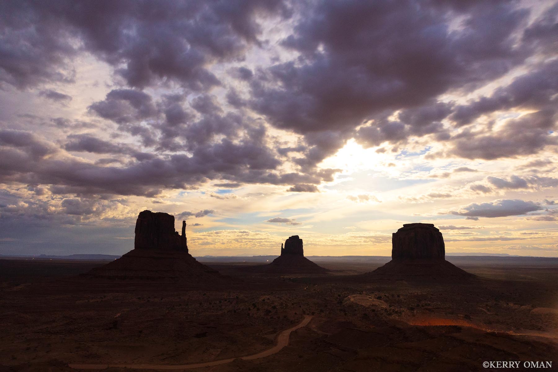 Desert Light Before the Storm Beneath a sky charged with shifting clouds, the iconic buttes of Monument Valley rise from the desert floor, silhouetted in golden...
