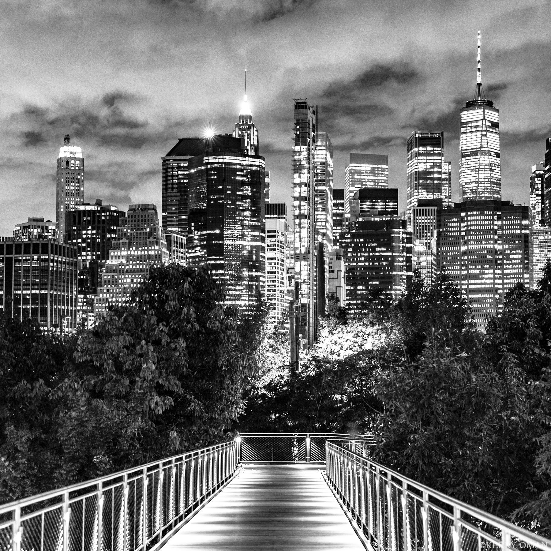 Crossing Into Light A pedestrian bridge rises from the trees of Brooklyn Bridge Park, guiding the viewer toward the illuminated towers of Lower Manhattan...