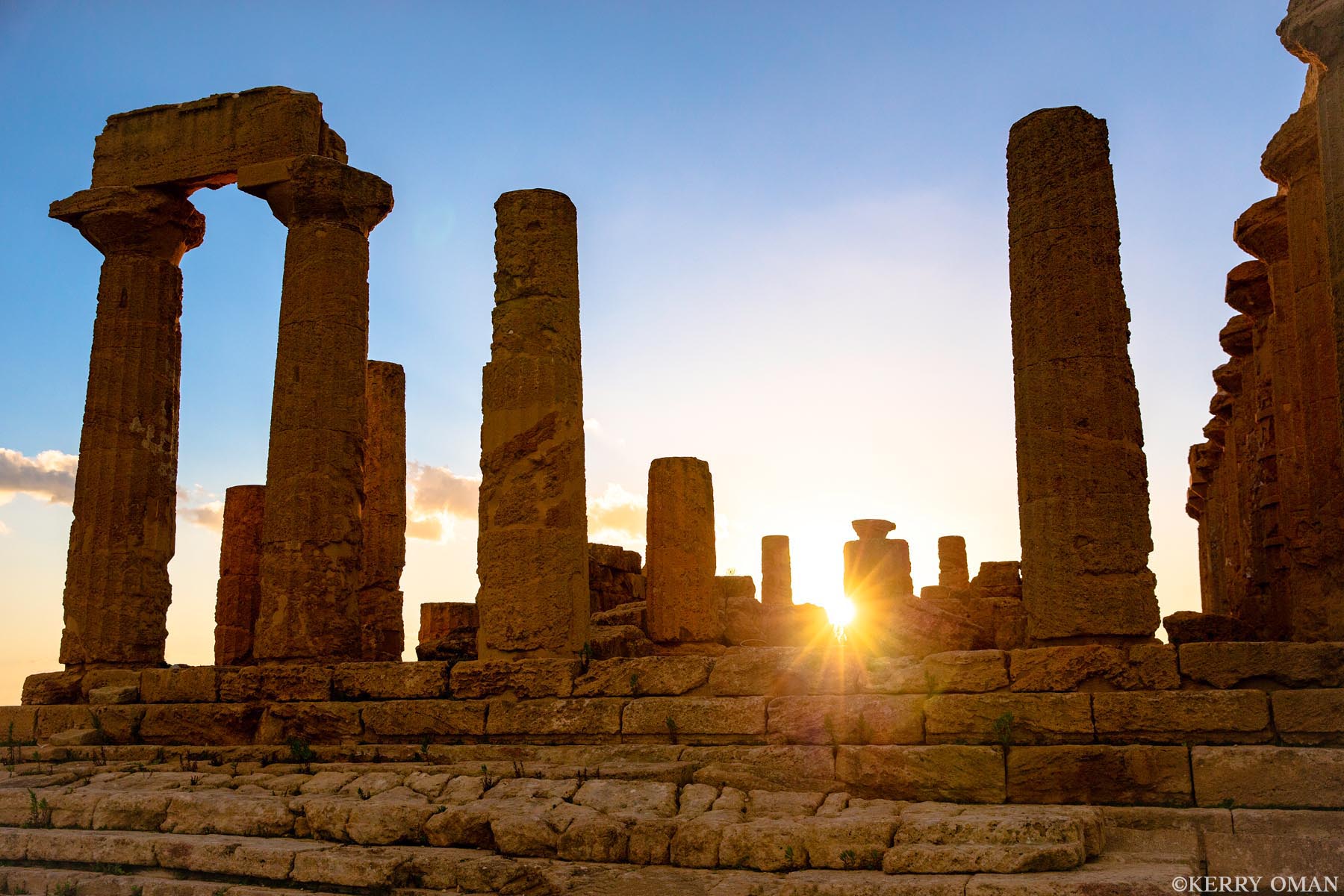Through the Columns of Time As the sun sets behind the ancient ruins in Sicily’s Valley of the Temples, a soft glow passes through the standing columns...